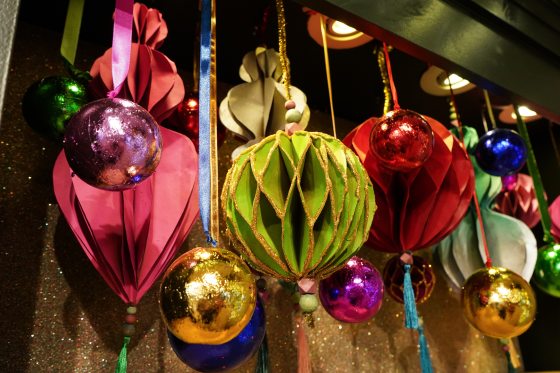 Handmade paper Christmas ornaments in green, red, and pink.